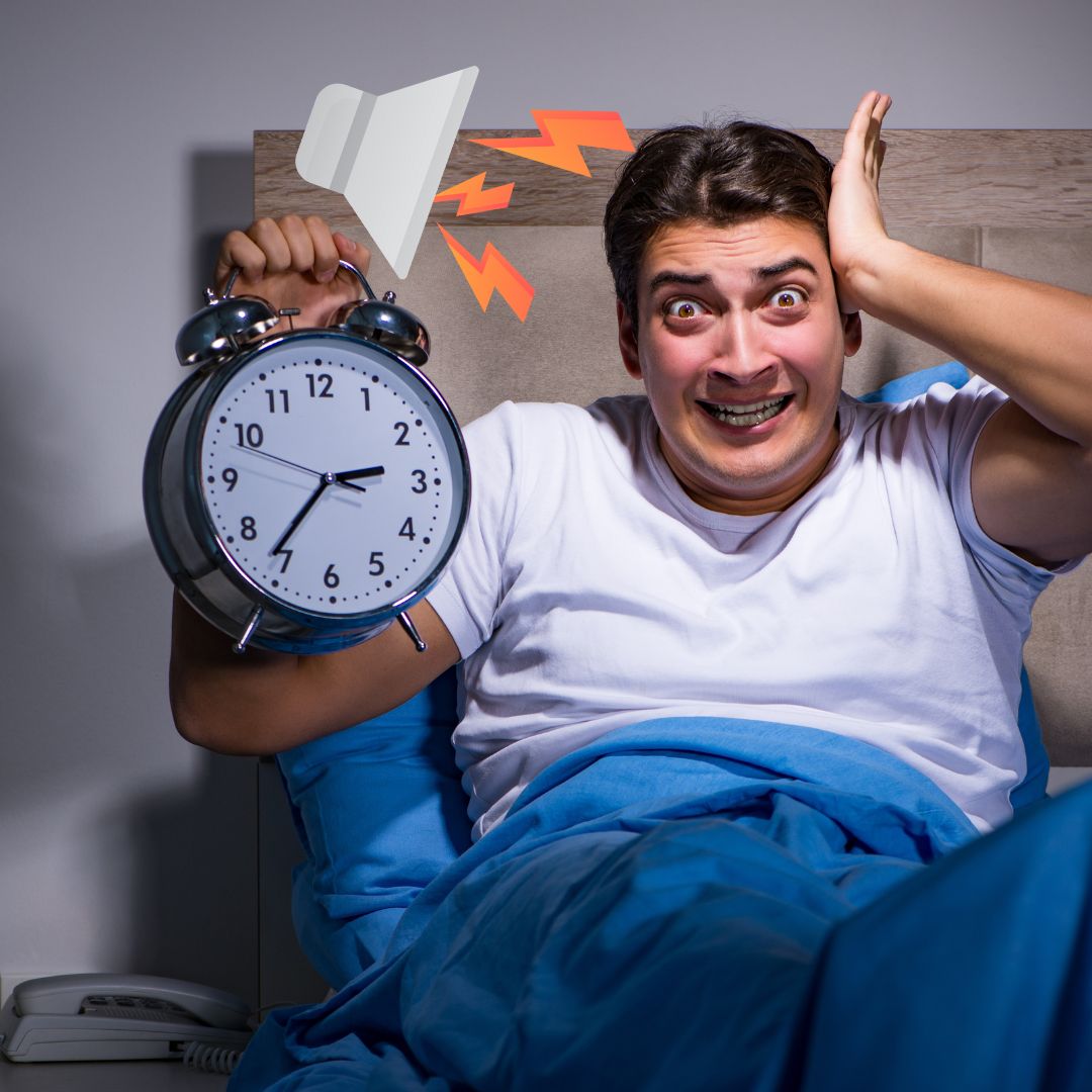 Een man met een wekker in zijn hand en die wakker wordt door het geluid.