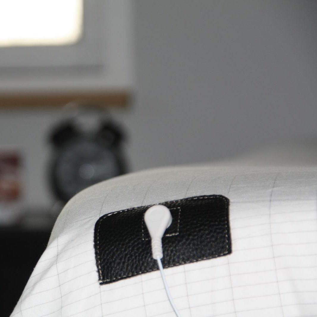 Aardingslaken op een bed met een wekker op de achtergrond