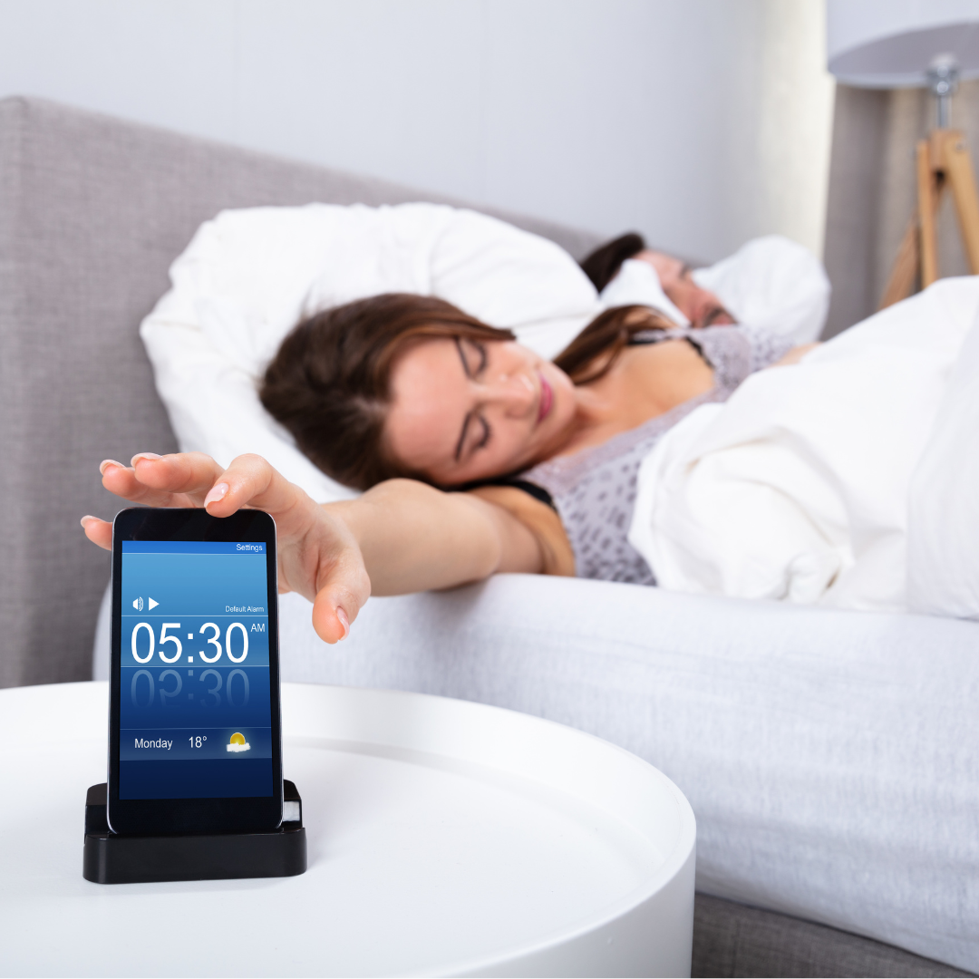 Vrouw reikt naar wekker om 05:30 terwijl ze een powernap neemt - blog over de voordelen en tips voor powernaps