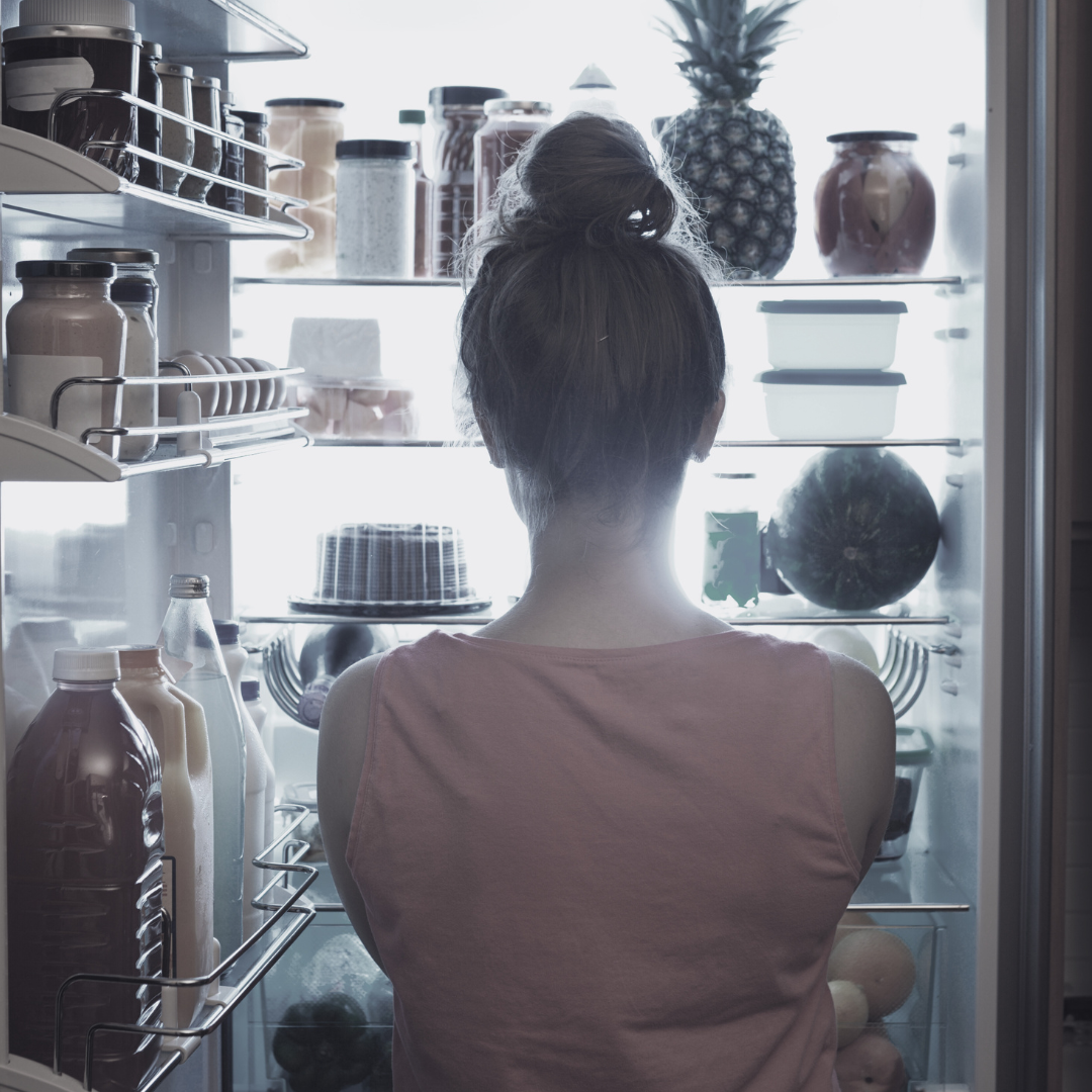 Una donna prende qualcosa dal frigorifero e si illumina il viso con una luce blu.