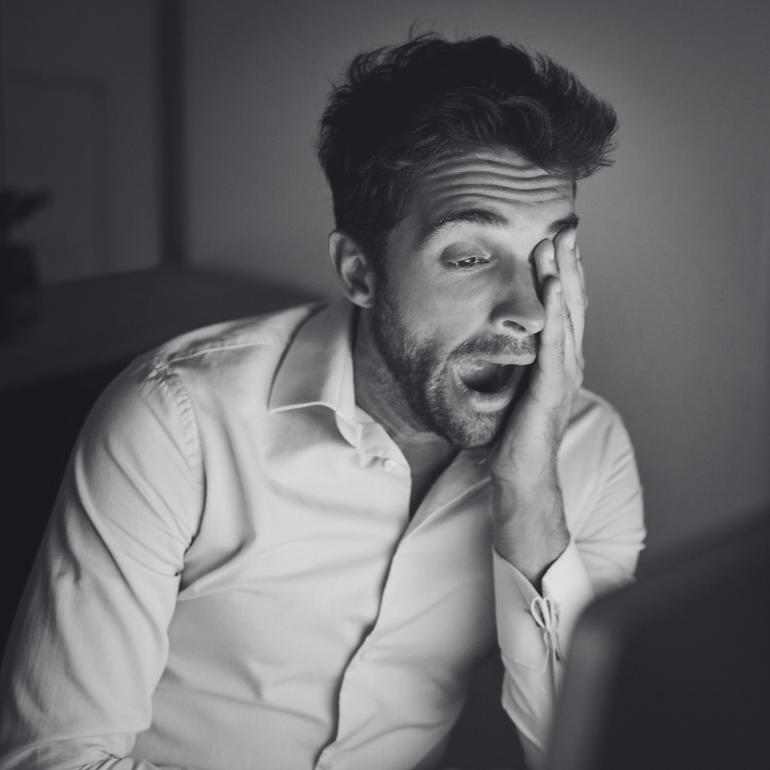 Man die zichtbaar moe is en achter de computer zit.