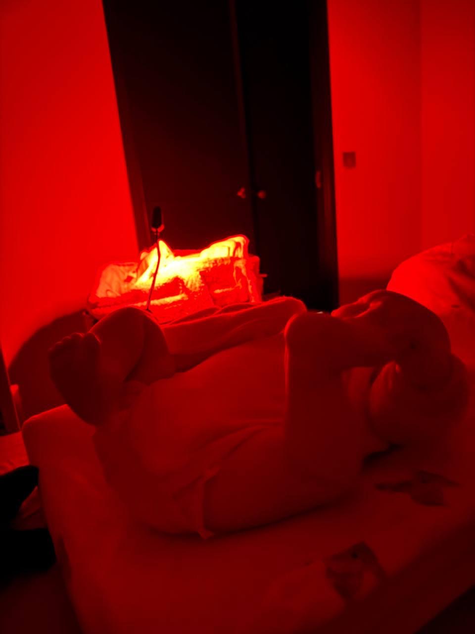 Baby die op bed ligt met de blauwlicht leeslamp