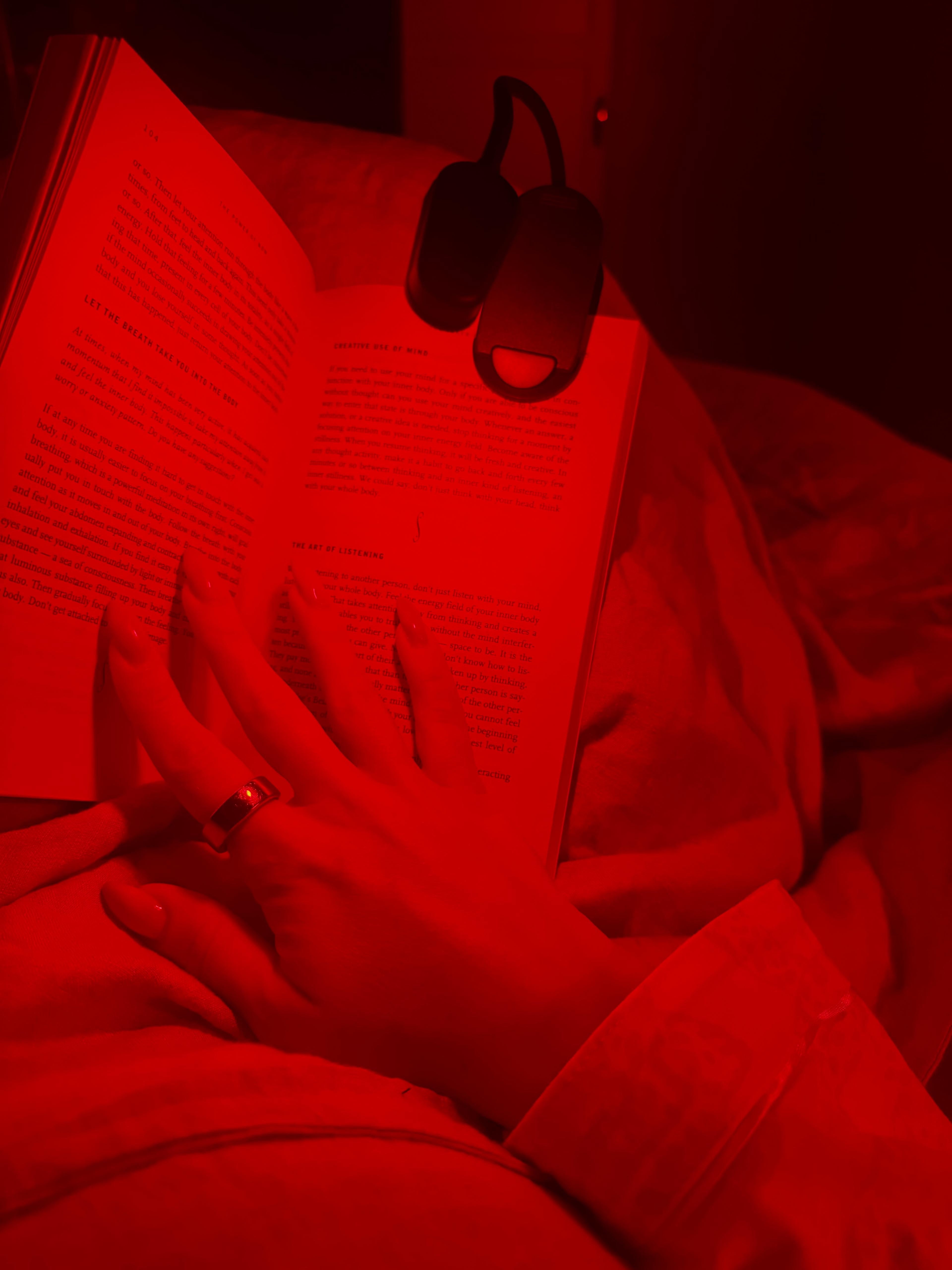 Voruw zit te lezen met de roodlicht leeslamp op een boek geklemd