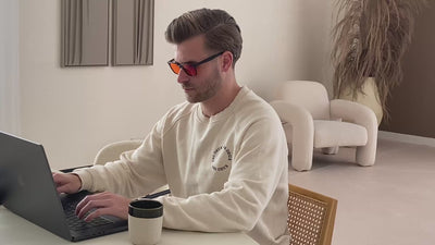 Man die achter de laptop zit met de blauwlicht bril op